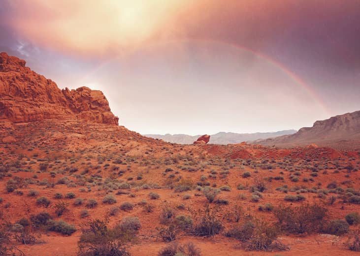 Red rock formations with a rainbow above