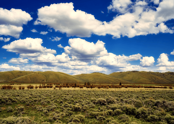 Sun shining on shrubland and large hills