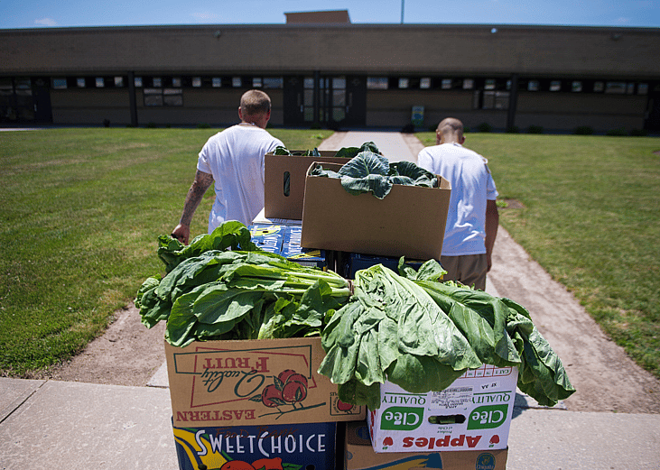 Inmates carry boxes of produce at correctional institute