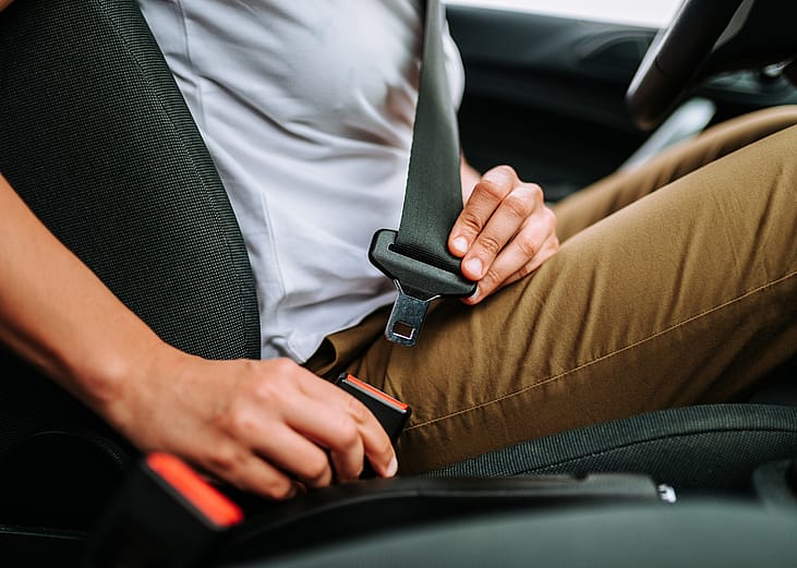 Close-up of woman in car fastening seat belt