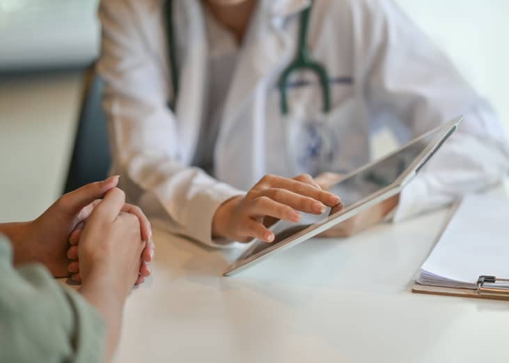 Doctor showing patient information on a digital tablet.