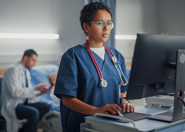 Acute care nurse at terminal in hospital room.