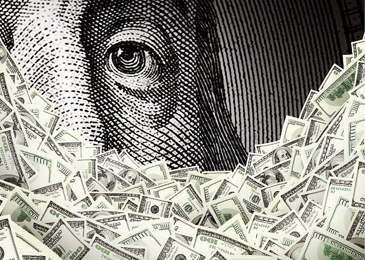 Close up of Benjamin Franklin portrait with hundred dollar bills in the foreground