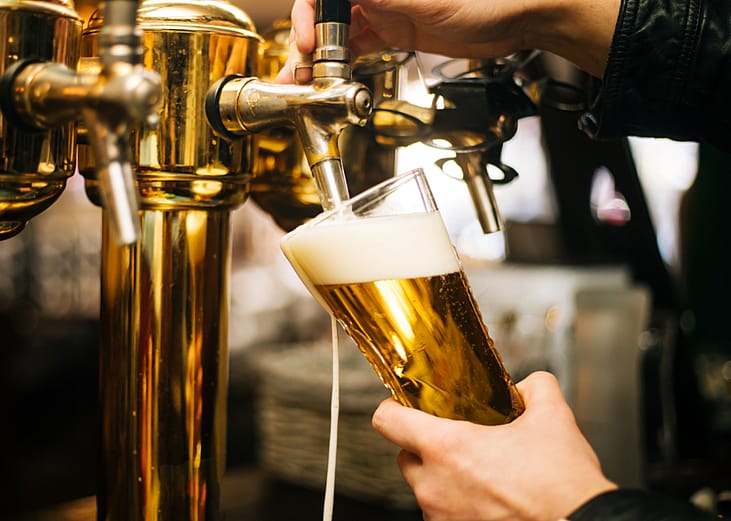 A bartender pours a pint of draft beer. 