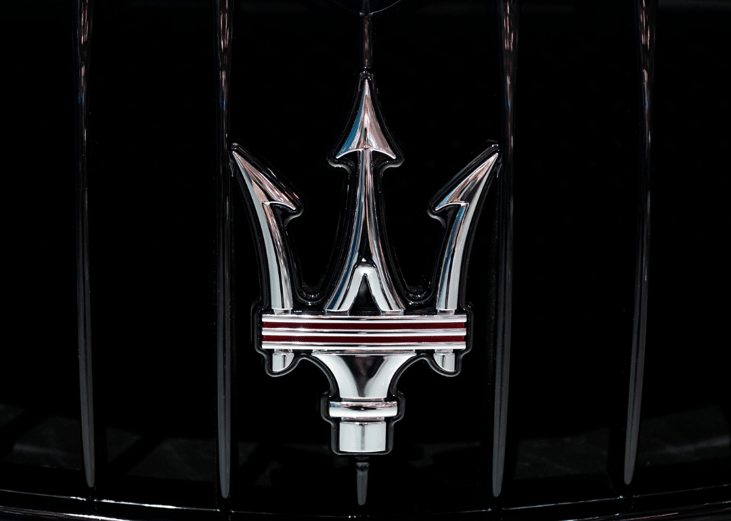 The Maserati logo as seen on the grill of a car.