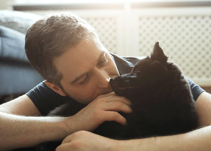 Owner hugging Schipperke dog.