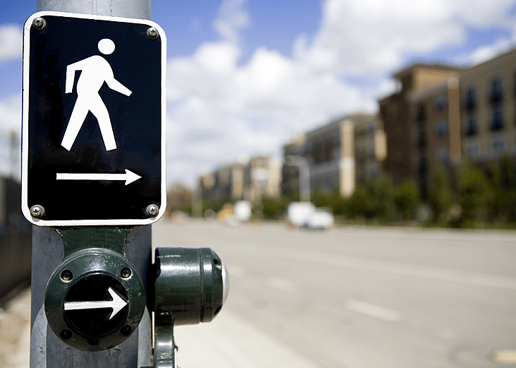 A lit pedestrian crosswalk sign on a road. 