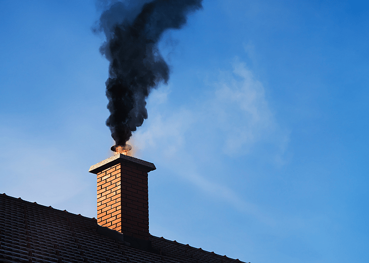 Black smoke coming out of a chimney on a residential home due to fire