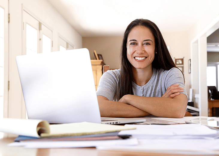 A smiling Latina woman sitting at a desk