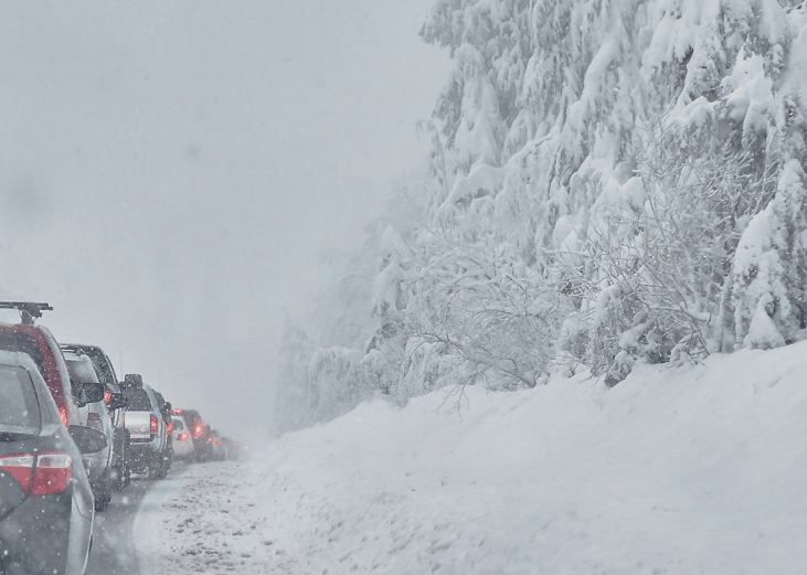 Cars driving along snowy road.