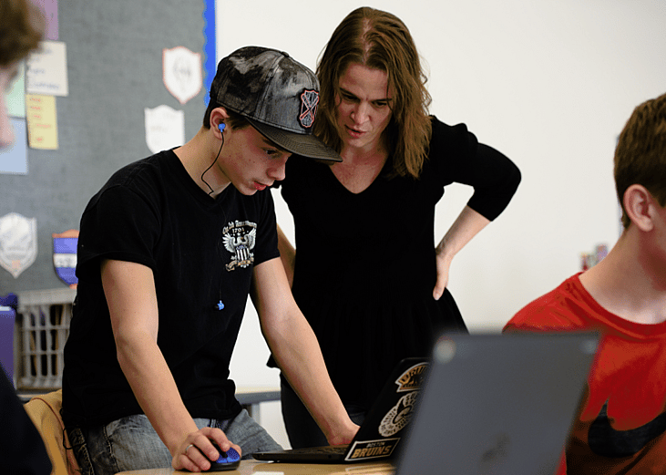 Teacher helping student on laptop