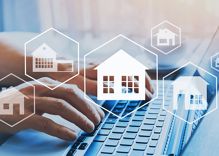Hands working over a keyboard with superimposed images of real estate holdings matted over the photo, symbolizing investments taking place online
