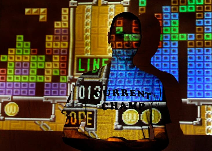 tetris game projected on the wall with player posing in the dark