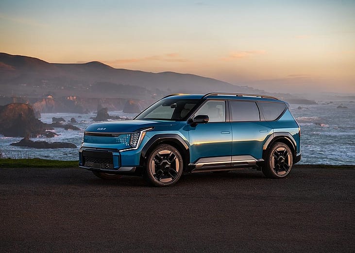 blue kia ev9 parked by ocean