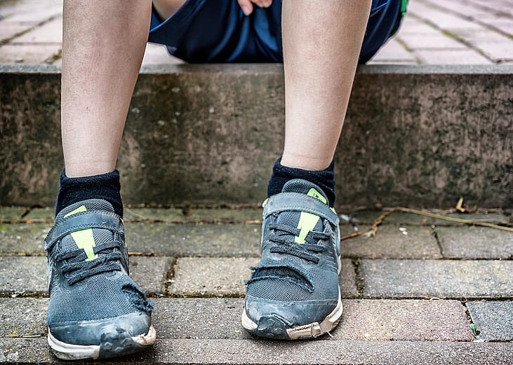 A child sits with torn shoes as a symbolic image on the subject of child poverty.