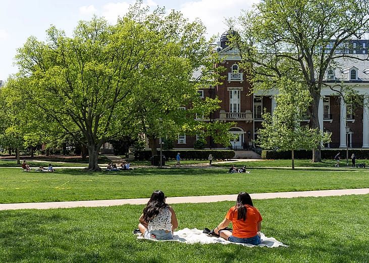 students sitting on the lawn at a college campus
