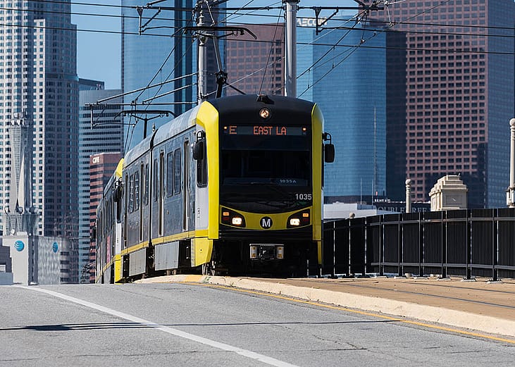 LA Metro E line train pulls into Boyle Heights with Downtown LA in the background