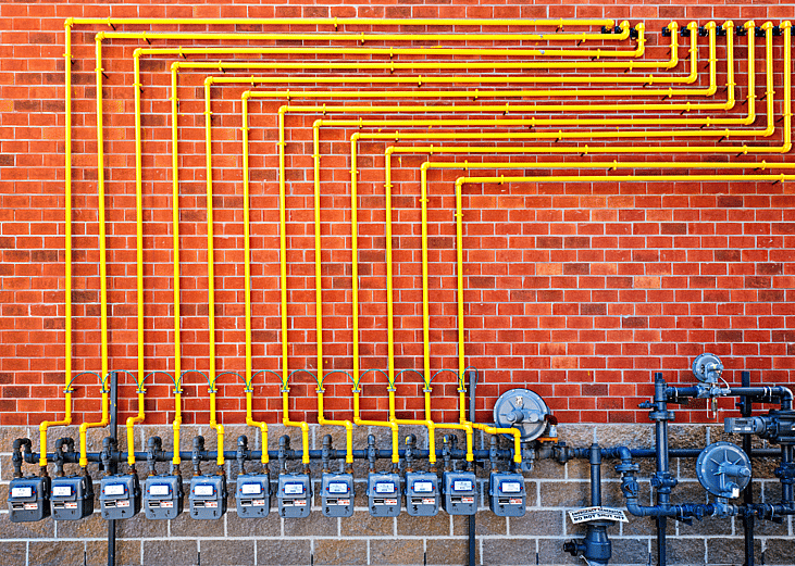 row of residential gas meters on a brick wall