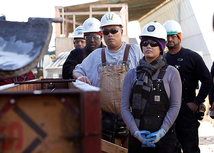 Students Marie Rowena Hall (right), Ryan Tagle (middle), and Michael Wells (left) learn how to work with concrete at JobTrain during laborers construction fundamentals training in Menlo Park, California.