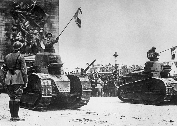 French soldiers holding flags and riding in tanks in front of the Arc de Triomphe on the Champs Elysees during a Bastille Day Victory Parade celebrating the end of World War I, Paris, France.