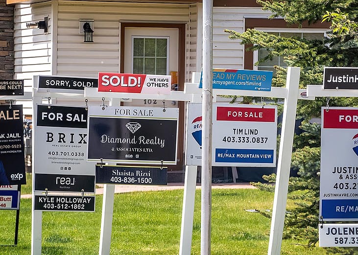 A row of signages are posted for homes for sale in Calgary, Alberta.