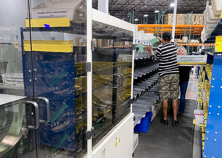 Sealed envelopes holding ballots cast in Maricopa County's presidential preference election in March zip through a high-speed scanner at Runbeck Election Services.