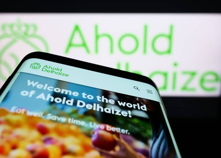 Mobile phone with website of Dutch company Koninklijke Ahold Delhaize N.V. on screen in front of business logo.