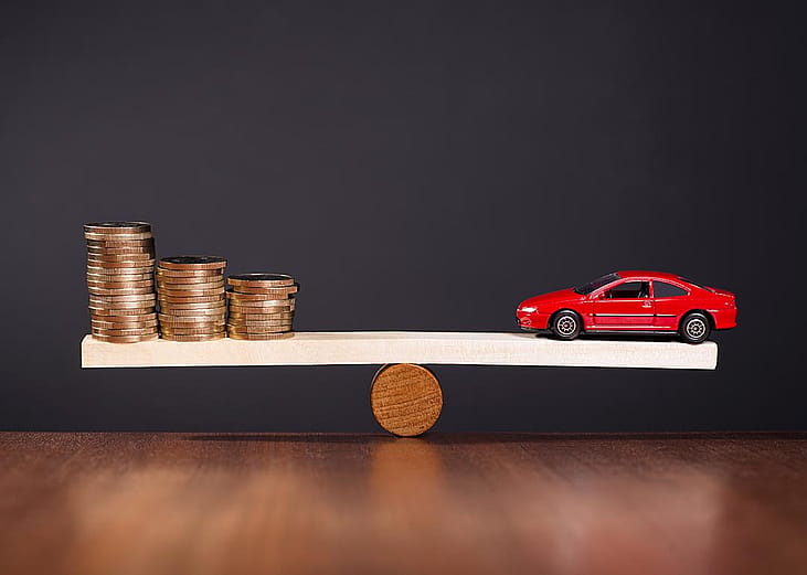 Concept of car value; selling car that is not paid off, illustrated by a seesaw balancing money on one side against a car on the other.