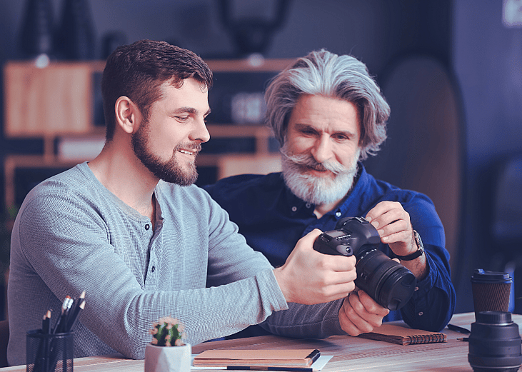 An older photograher mentors a younger one.