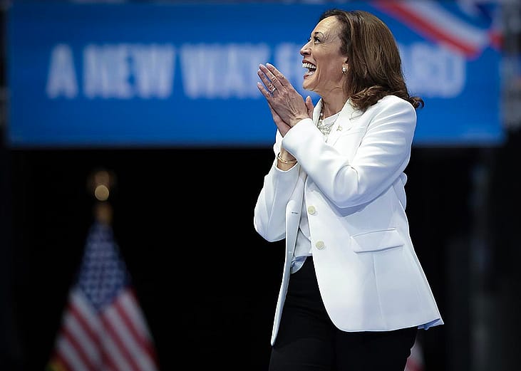 Democratic presidential nominee, U.S. Vice President Kamala Harris wearing white, greets the crowd as she arrives on stage at a campaign rally at the Enmarket Arena August 29, 2024 in Savannah, Georgia.