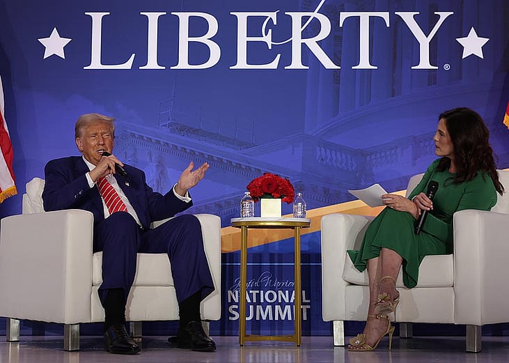 On stage, Donald Trump speaks as Co-founder of Moms for Liberty Tiffany Justice looks on during the 2024 Joyful Warriors National Summit on August 30, 2024 in Washington, DC.