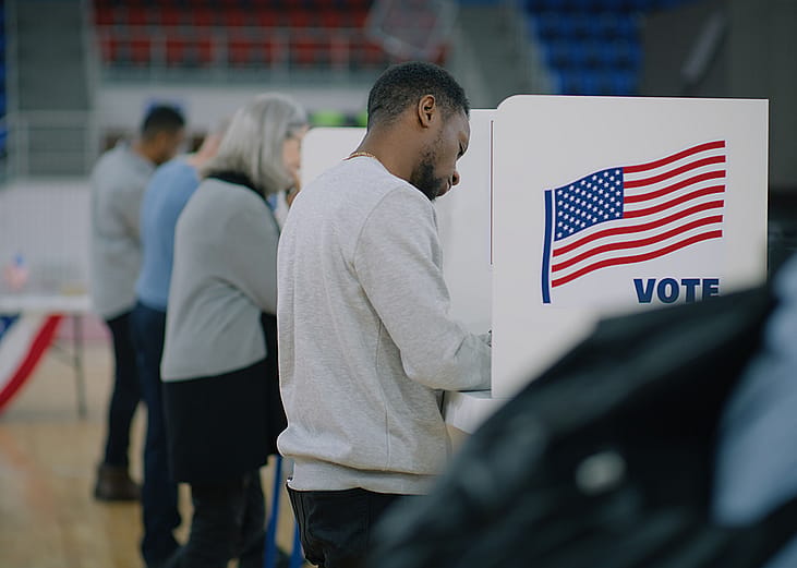 Male voter with bulletin in hands comes to a voting booth on US election day. 