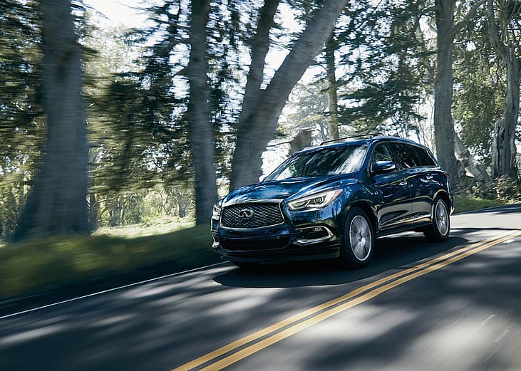 Blue 2020 INFINITI QX60 driving on the road.