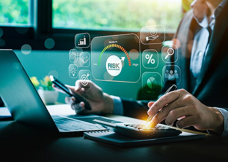 A business professional identifying and assessing risk management by using a laptop and holographic concepts of worker safety and insurance are shown.