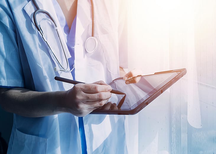 A medical professional using a digital tablet pointing out health insurance information.