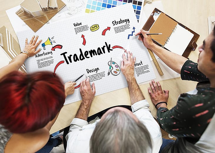 Three people looking at process of marketing and trademarking. business, overhead view.