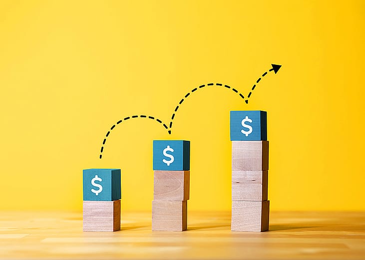 Concept of investment growth represented by an increasing stack of cubes with dollar signs.