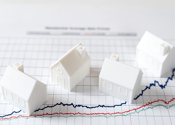 Four pieces of 3D models of houses over an investment chart.