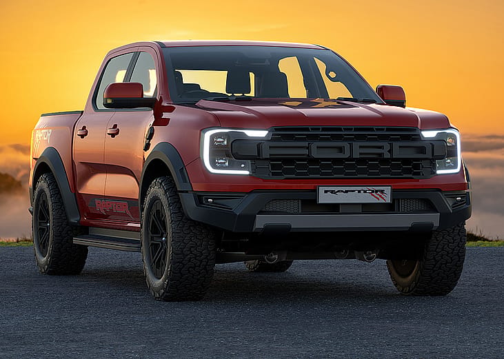 A red 2023 Ford Ranger Raptor with the sun setting in the background.