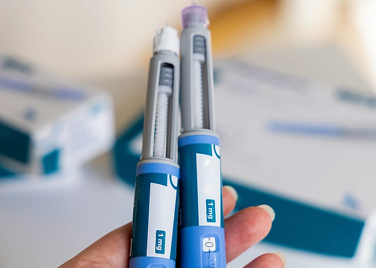 A hand holding two Ozempic pens for diabetics.
