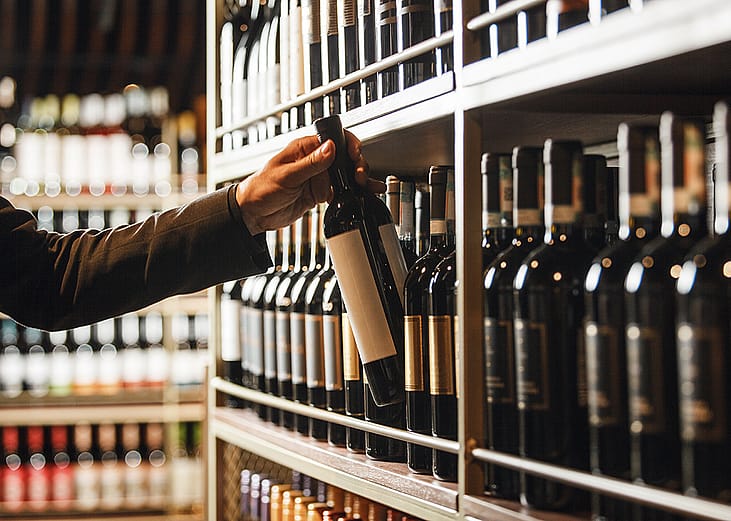 An extensive wine cellar collection and a wine bottle is being carefully picked.