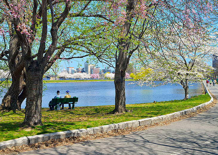 Two people sitting on a bench by the Charles Rives Esplanade in Boston, Massachusetts.