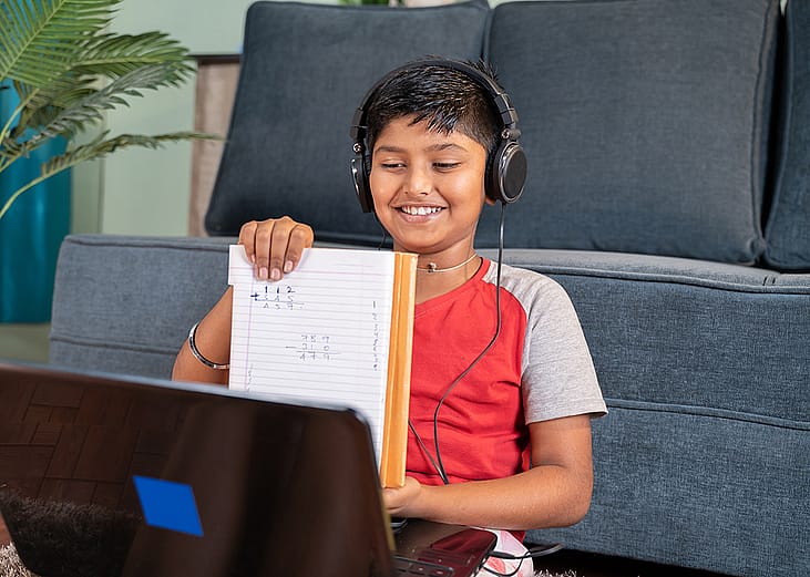 A kid virtually interacting with a tutor using a laptop.