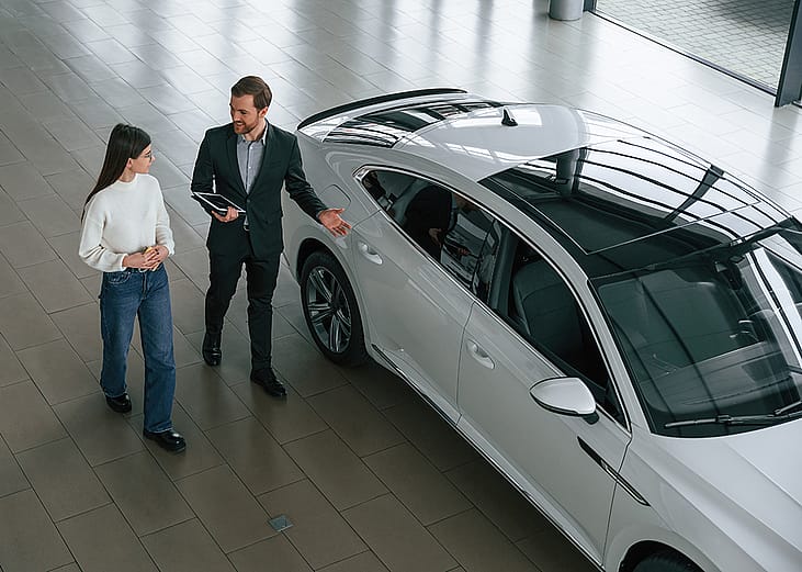 A woman choosing a new car in a dealership while an agent assists.