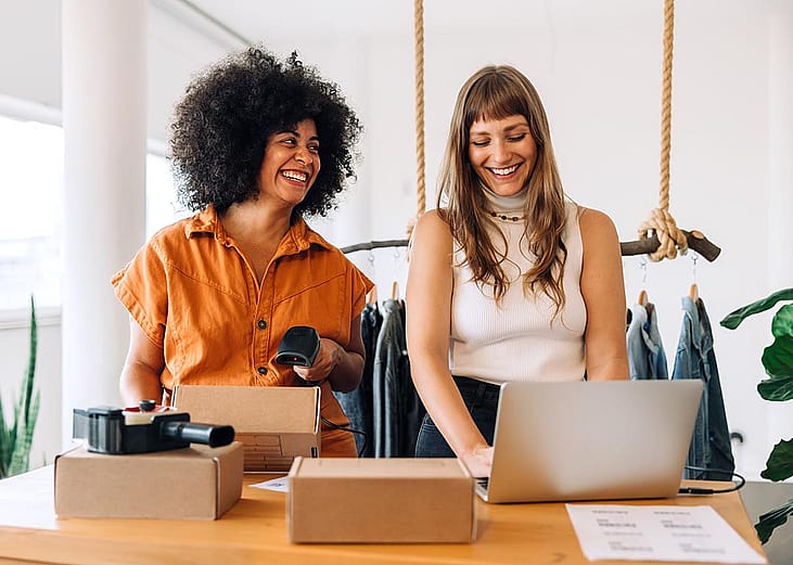 Two happy businesswomen preparing orders for e-commerce company.