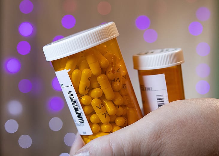 Person holding two bottles of prescription medicines.
