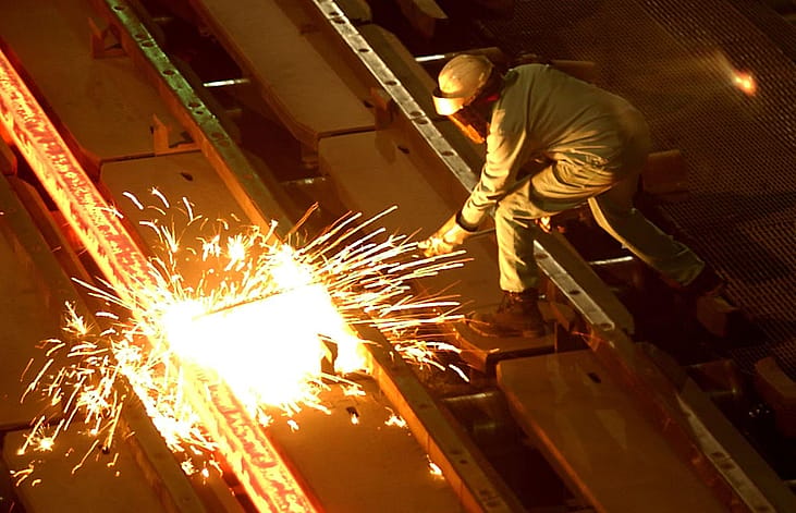 A worker cuts through a glowing 2,000 degrees Fahrenheit "billet" at the TAMCO steel mini mill