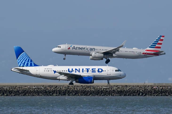 A United Airlines plane is taxiing to takeoff as an American Airlines plane lands at San Francisco International Airport