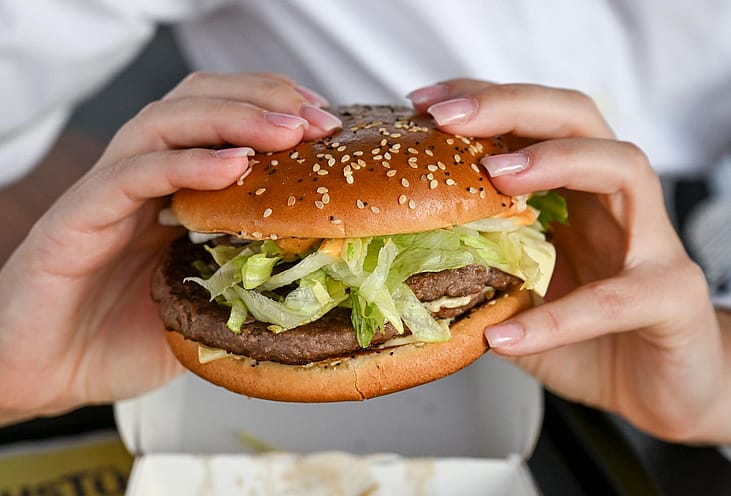 A photo of a woman holding a burger with two hands