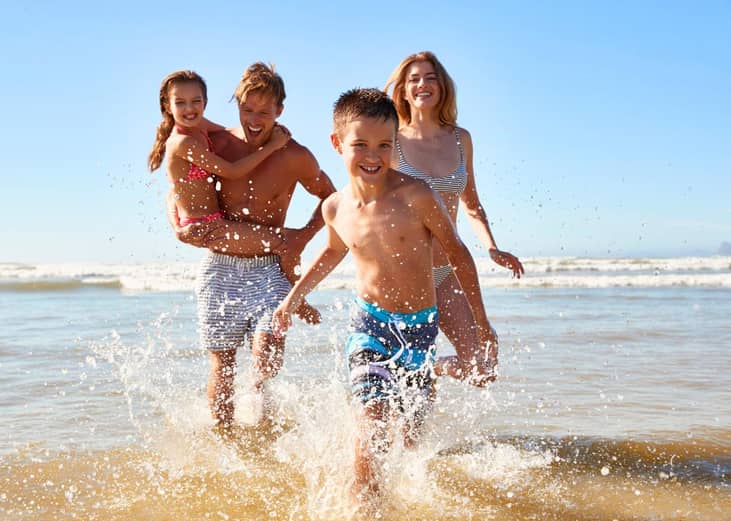 Family running on the beach in the summer of 2023.